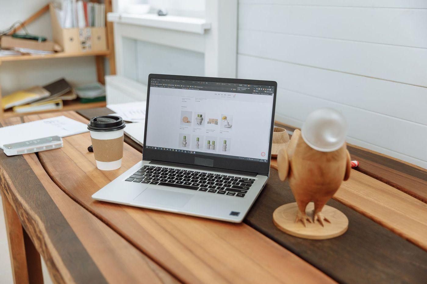 Arbeitsplatz mit Laptop, Kaffeetasse und Holzfigur