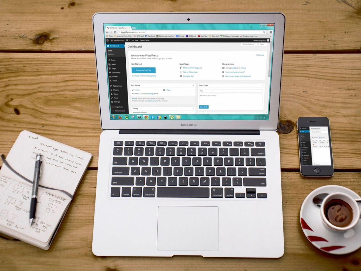 Laptop mit geöffnetem WordPress-Dashboard, daneben Smartphone, Notizbuch und Kaffee
