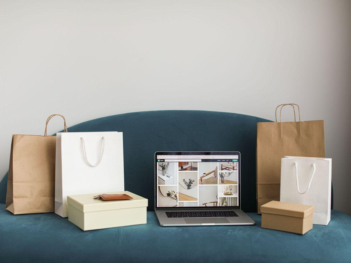 Einkaufstüten und Pakete neben einem Laptop mit Online-Shop